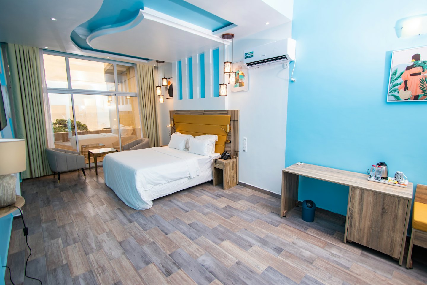 Camera d'albergo con letto matrimoniale e due poltrone grigie.