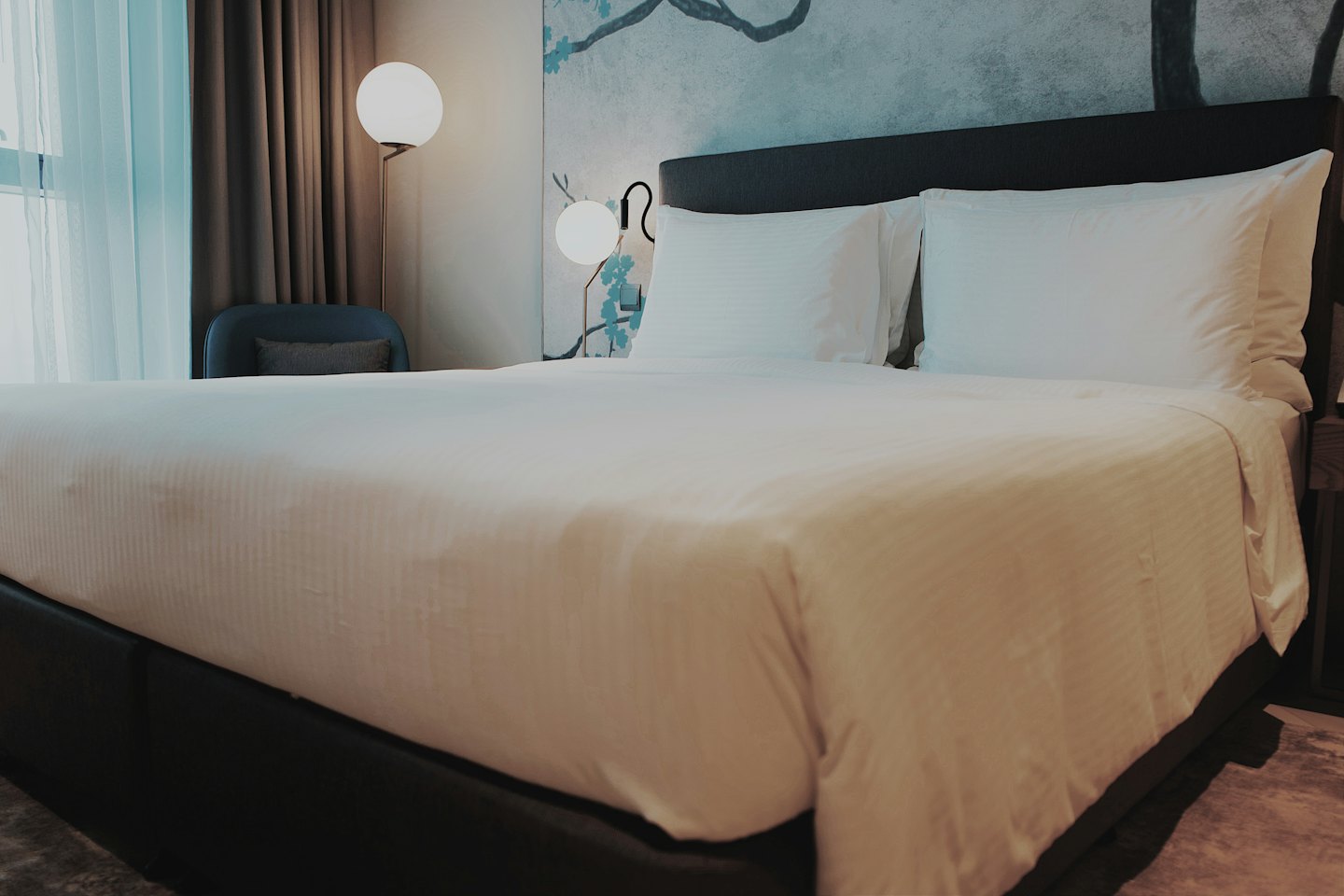 Letto king-size con lenzuola bianche in una camera d'albergo.