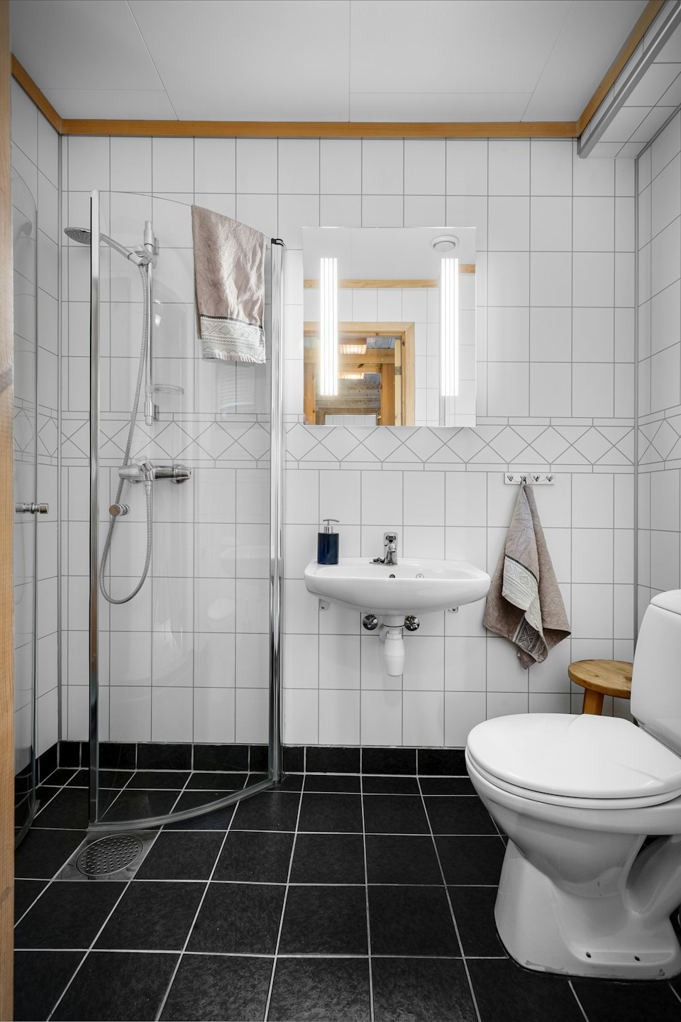 Bagno moderno con pareti piastrellate bianche e doccia in vetro.