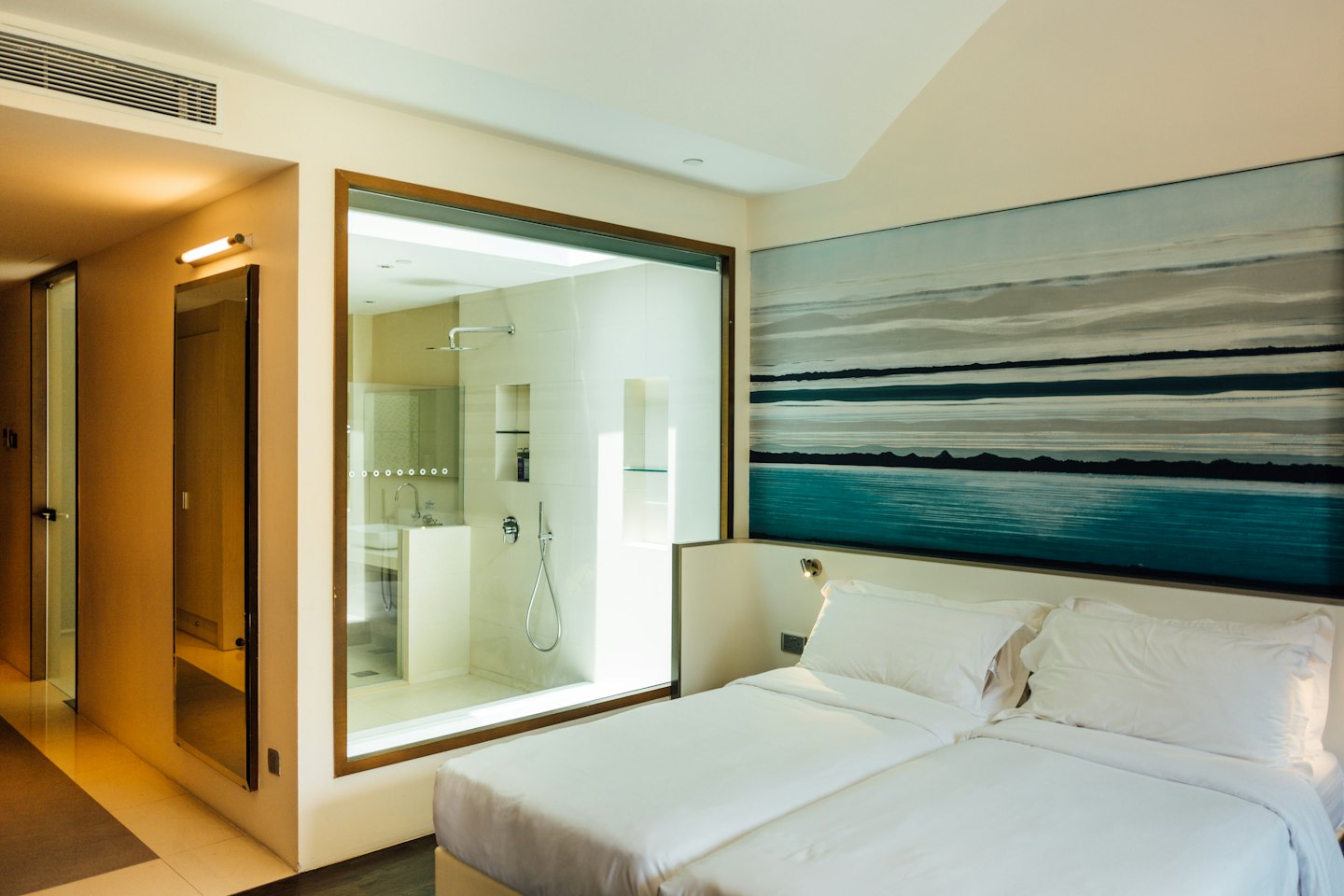 Camera d'albergo moderna con due letti e un quadro astratto alle pareti.
