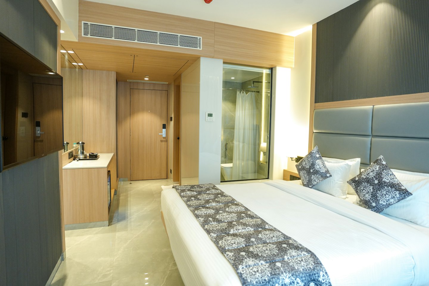 Camera d'albergo moderna con letto ben fatto e bagno.